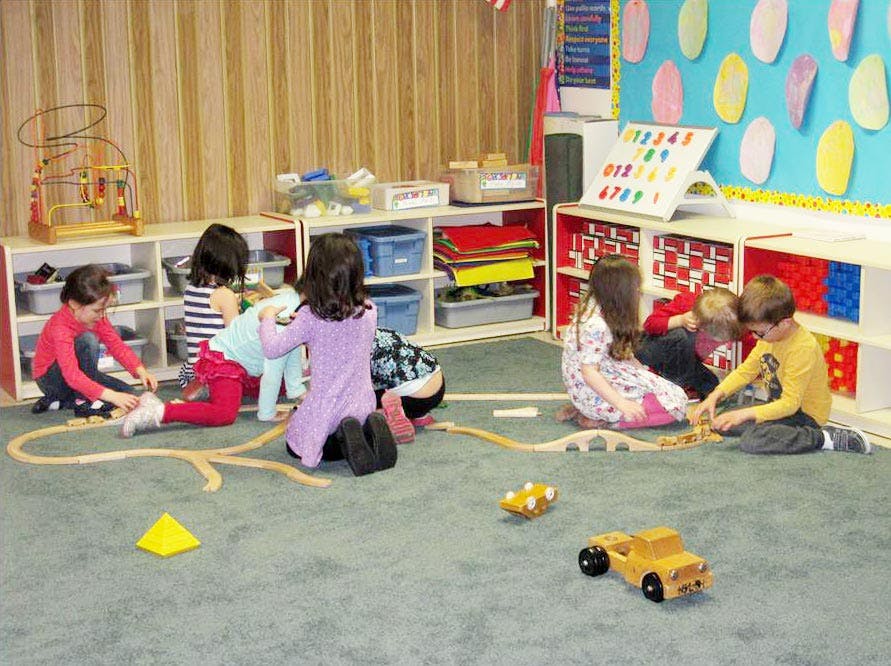 Children playing with toys on a carpeted floor in a classroom
