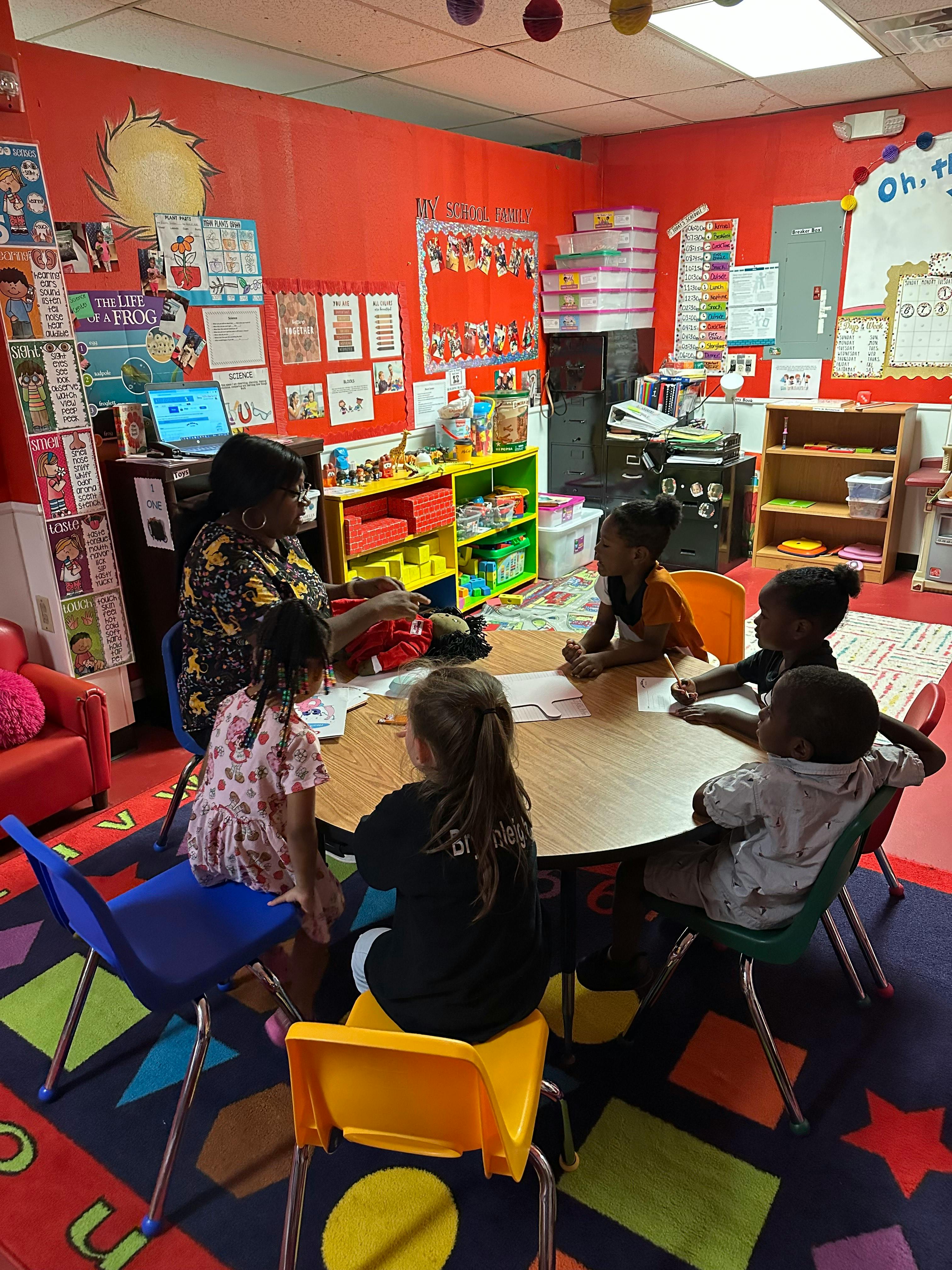 Adult and children sitting around a table in a classroom