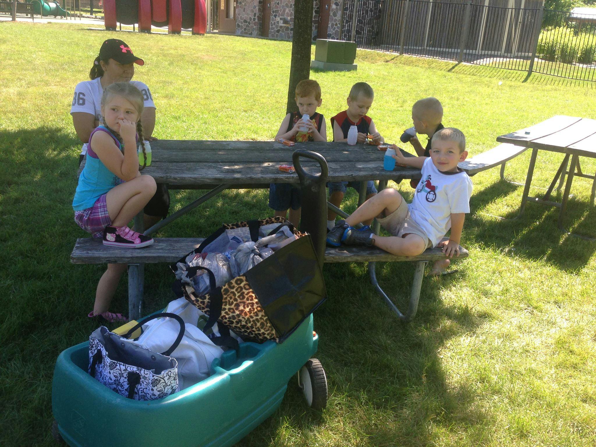 Adult and children sitting at a picnic table outdoors