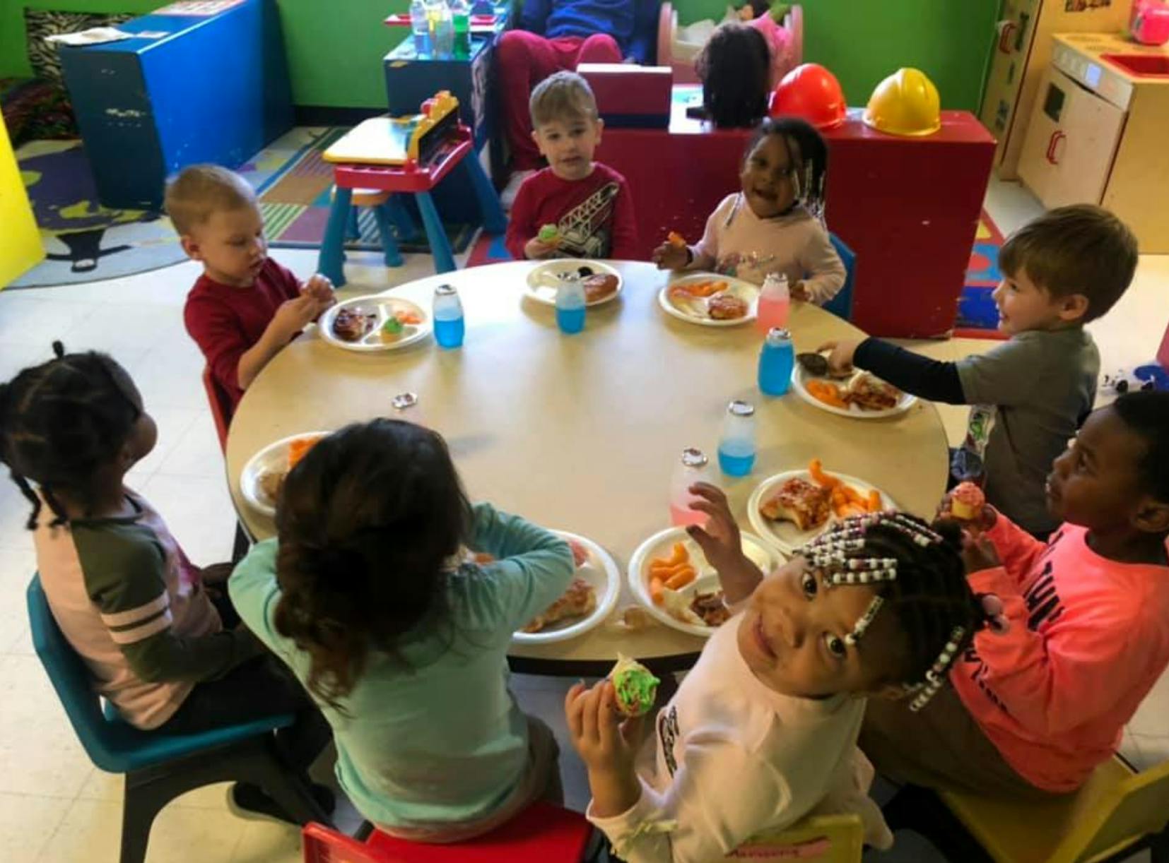 Children sitting around a table with plates of food