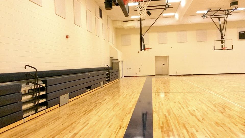 Empty gymnasium with bleachers and basketball hoops