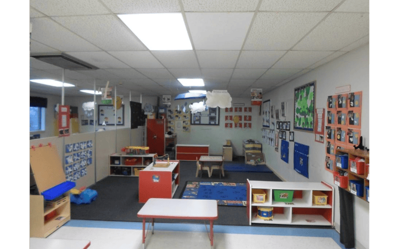 Classroom with tables, shelves, cubbies, and artwork on the walls