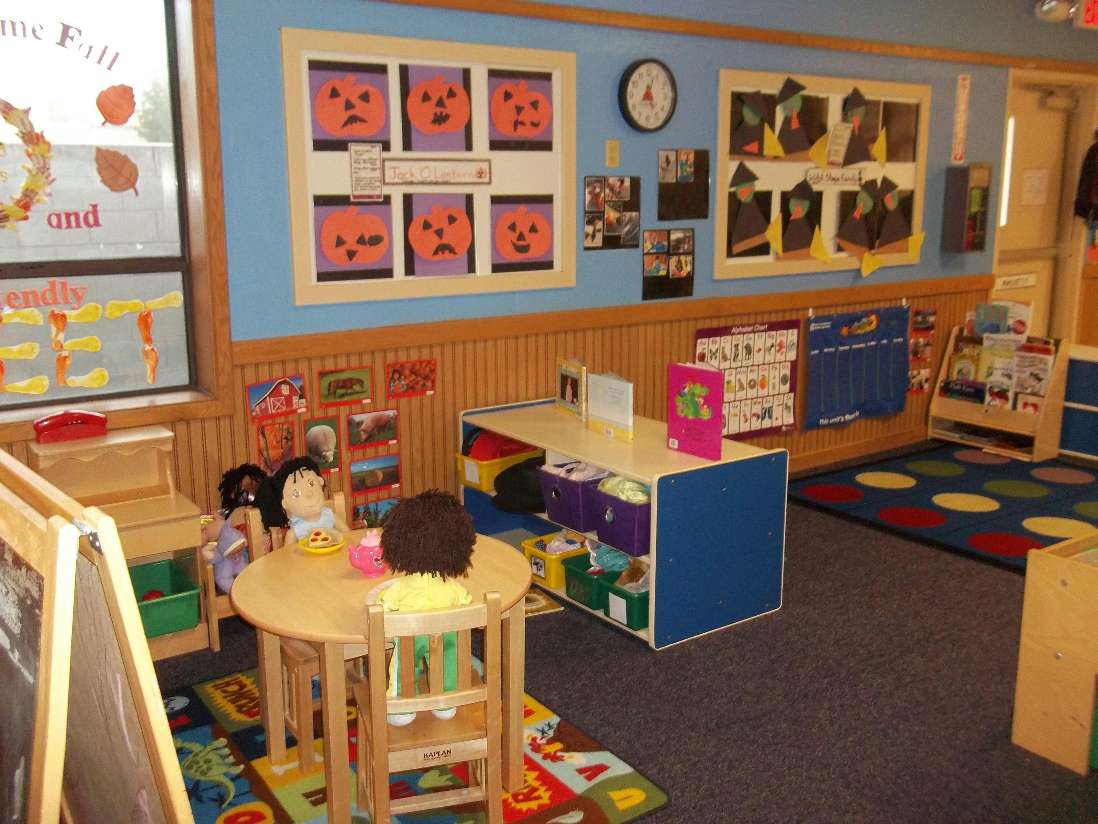 Doll sitting at a small table in a classroom with Halloween decorations