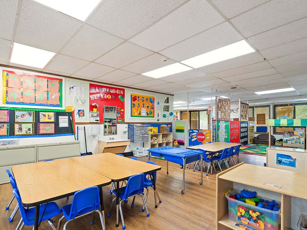 Classroom with small tables, chairs, and learning materials on the walls