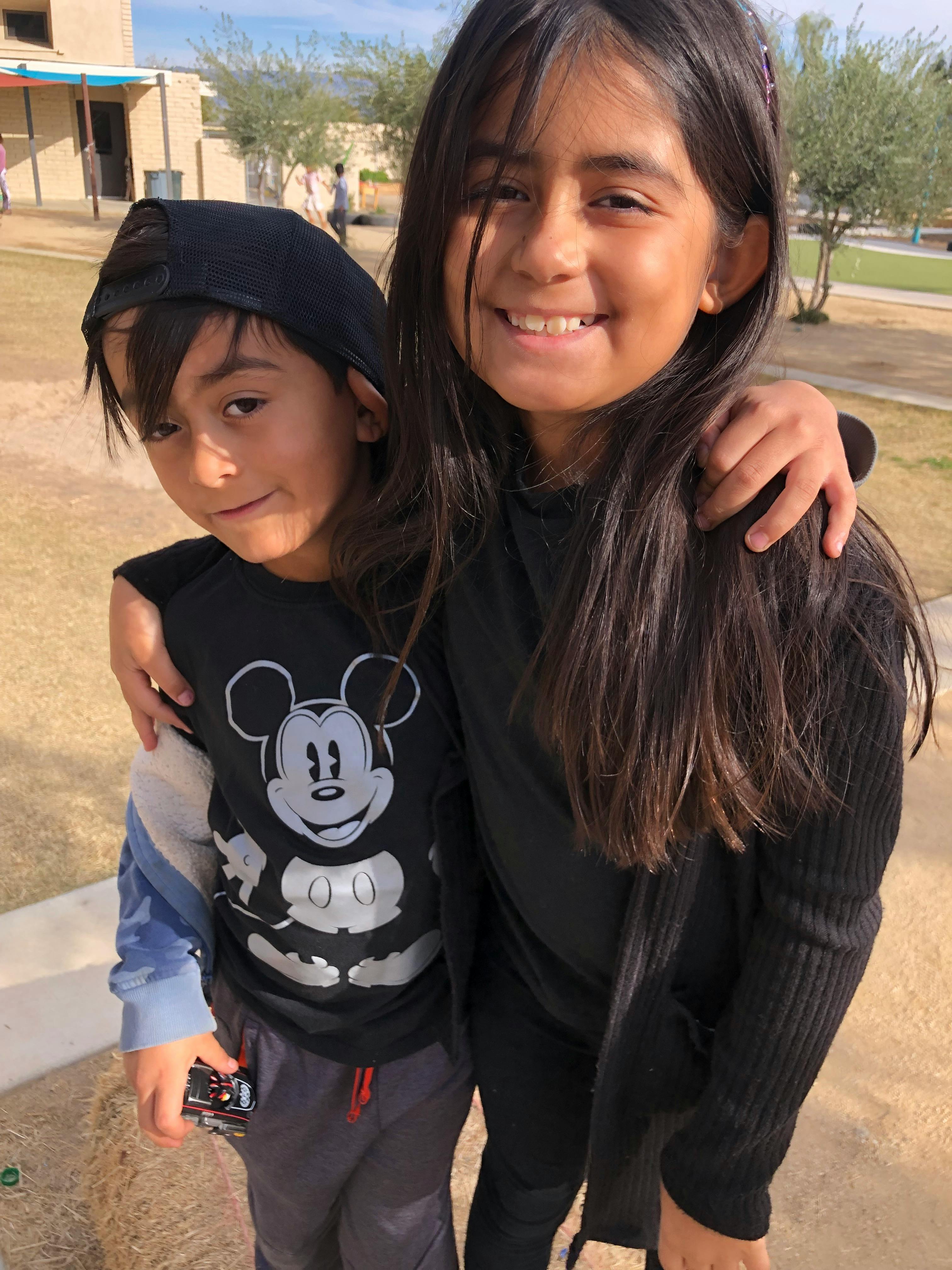 Two children standing with arms around each other