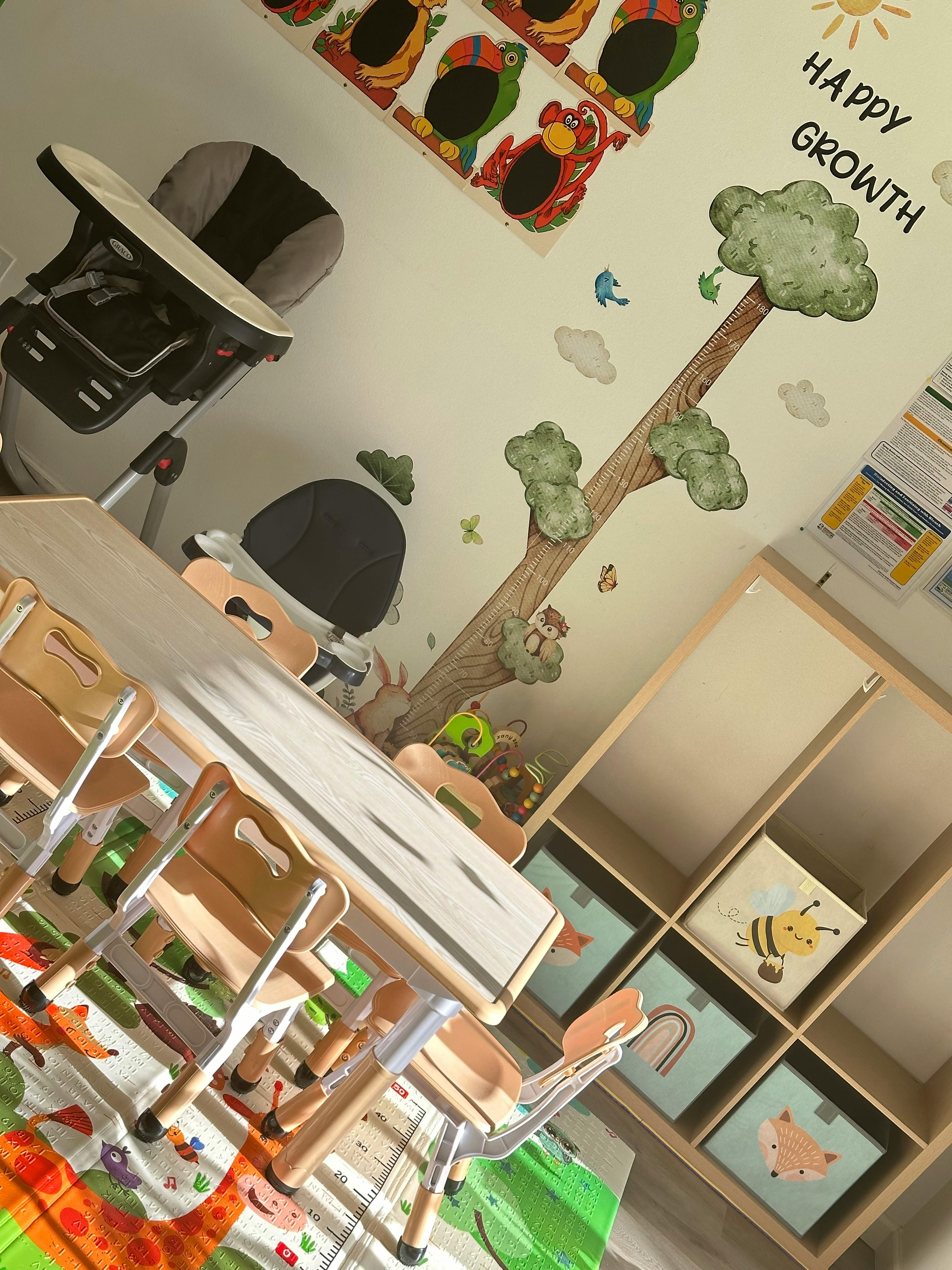 Child's high chair next to a table and chairs in a room with wall decals