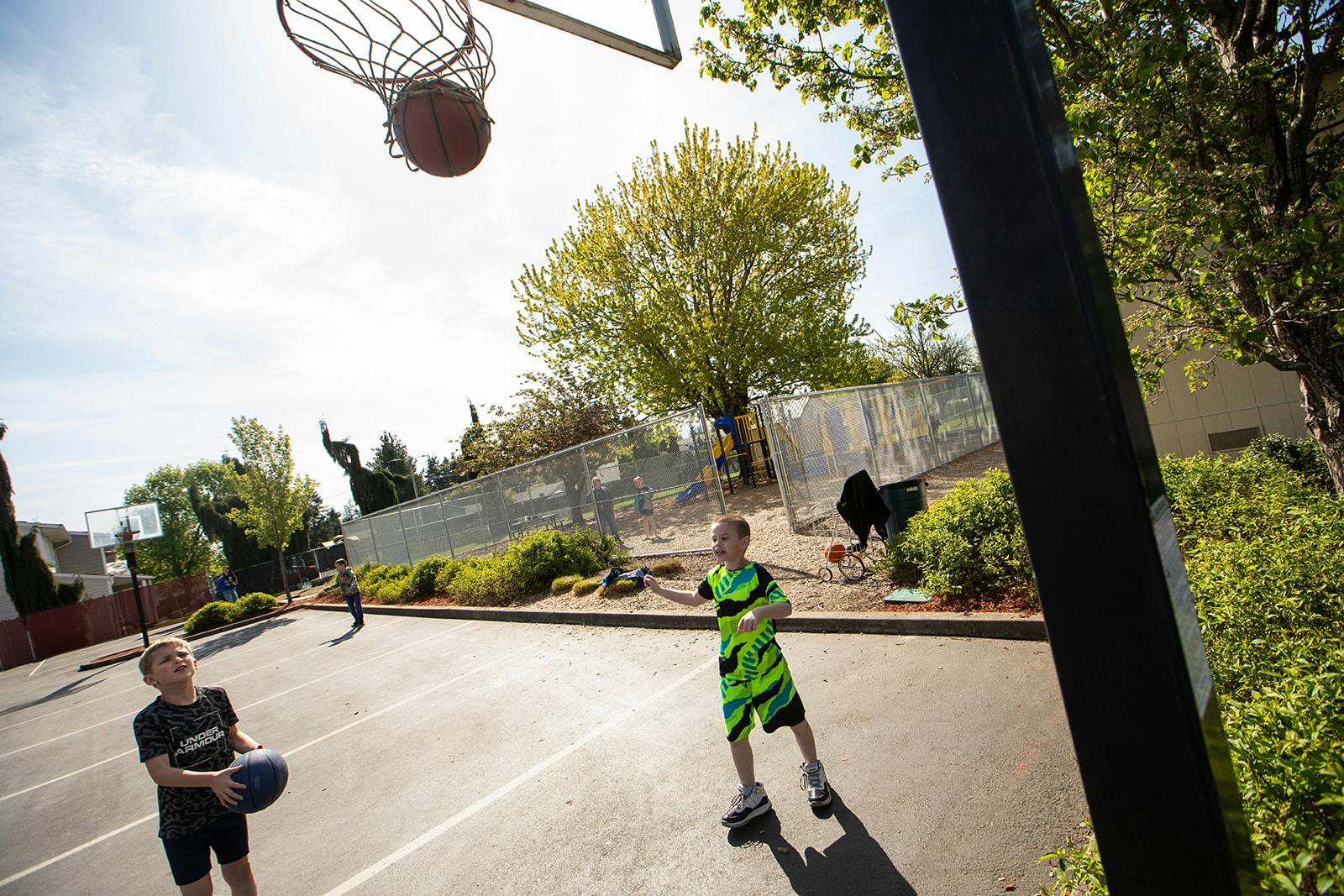 Basketball in a hoop with children on a court