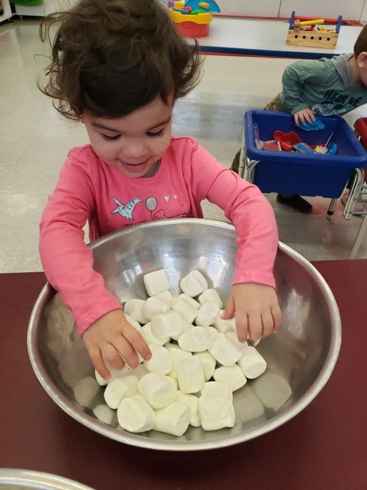 Child playing with marshmallows in a bowl
