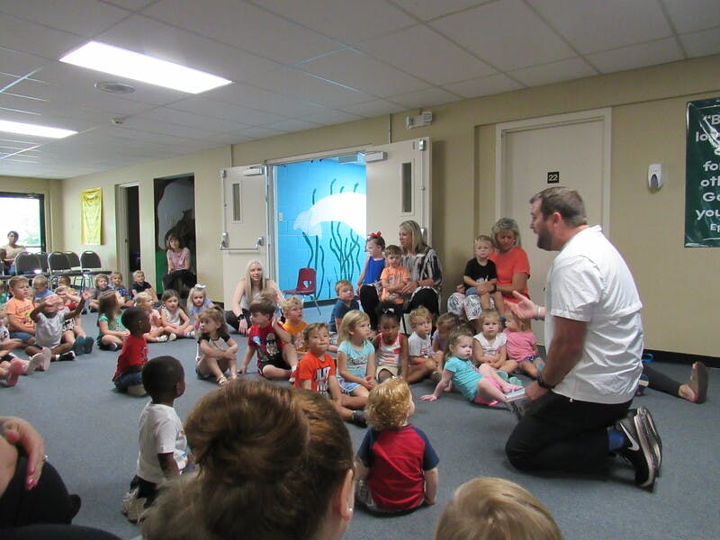 Adult speaking to a group of children sitting on the floor