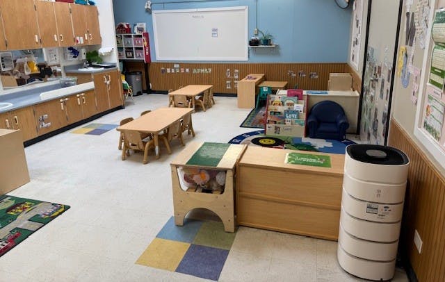 Empty classroom with small tables and chairs, cabinets, and a whiteboard