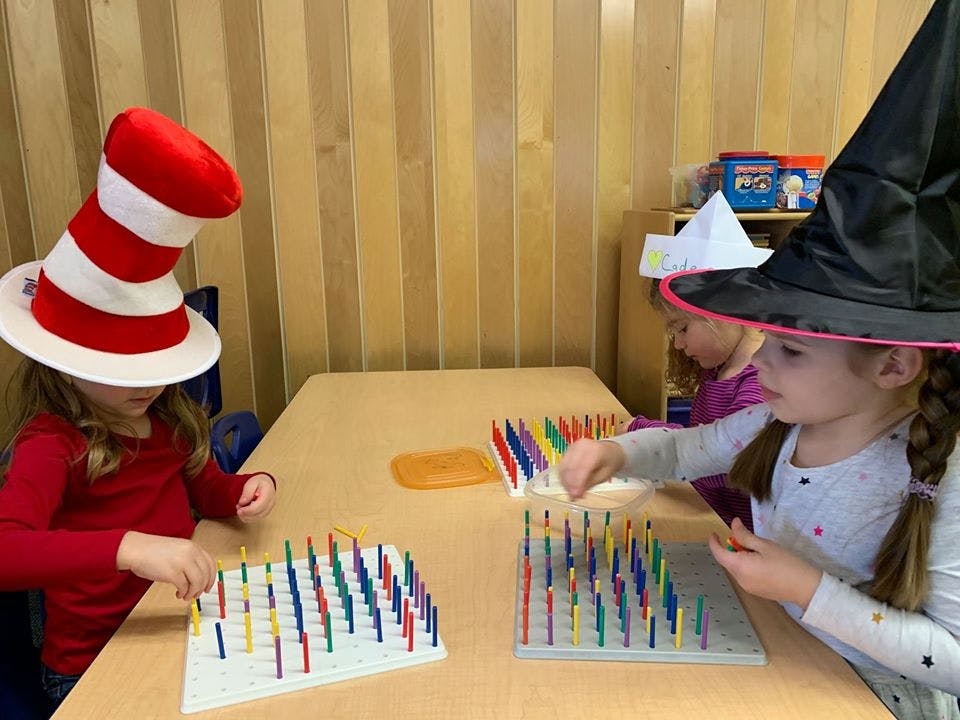 Two children wearing hats playing with colorful pegs on boards atable