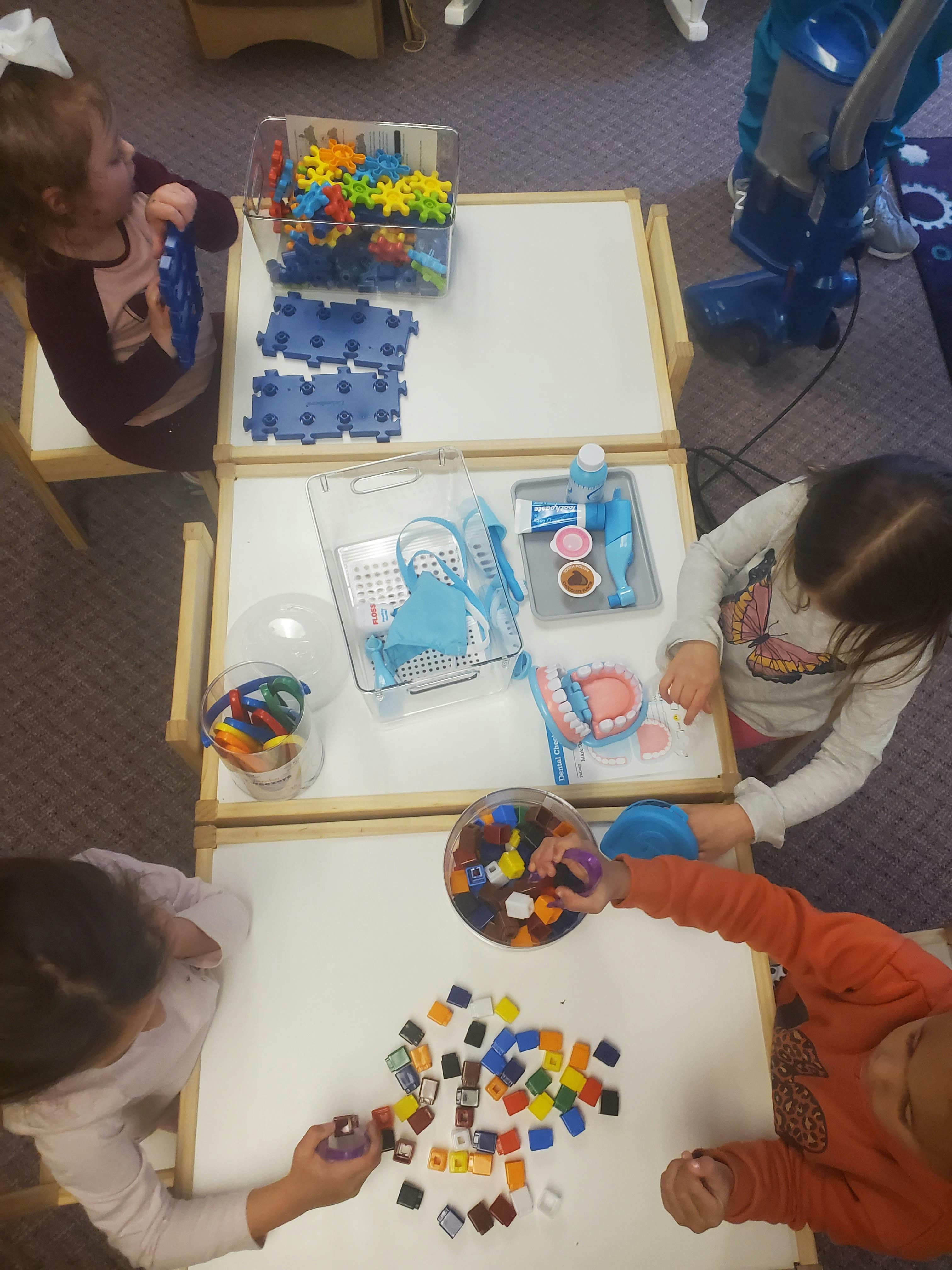 Children playing with toys at tables in a classroom