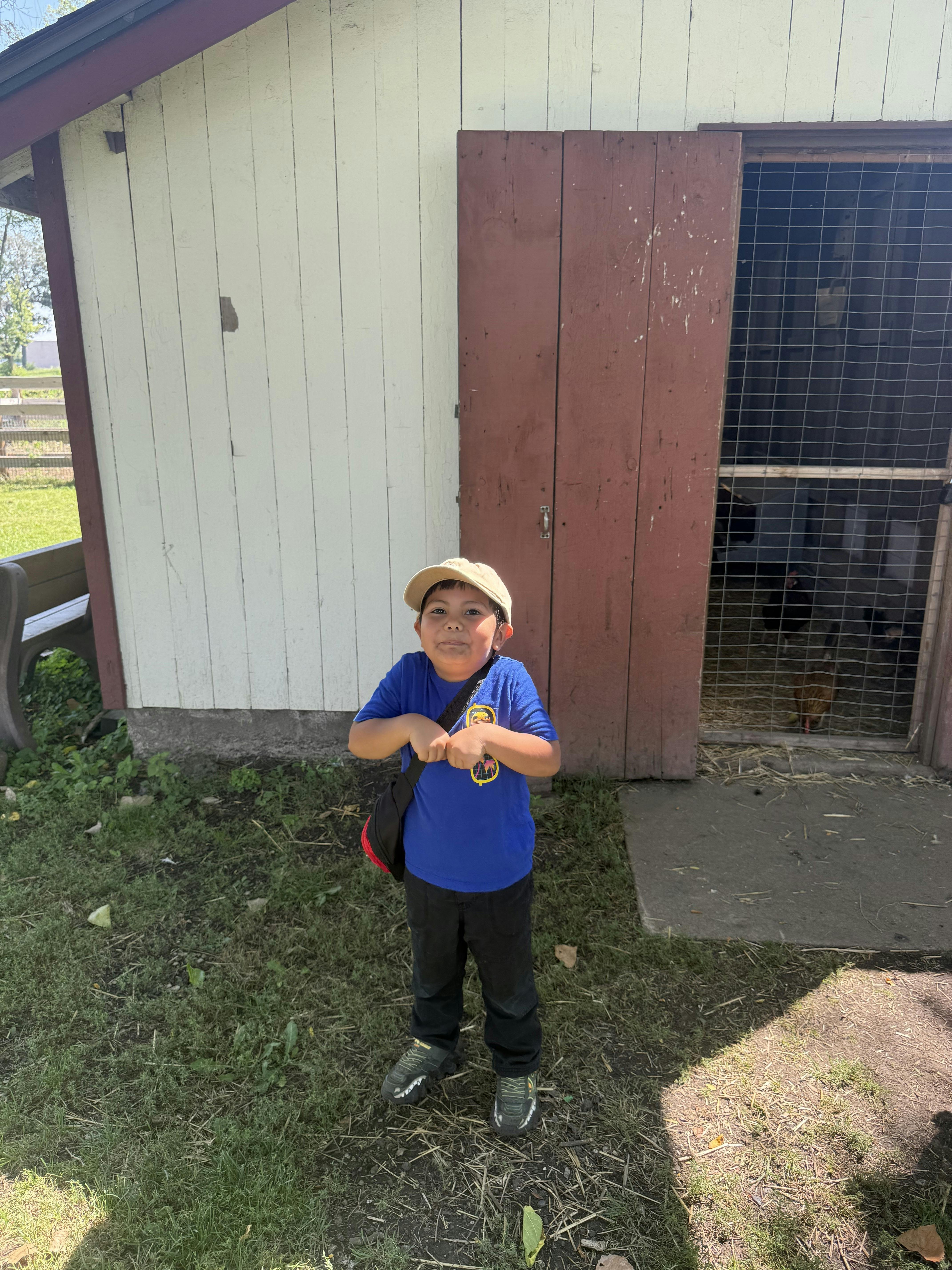 Child in a blue shirt and hat standing in front of a building