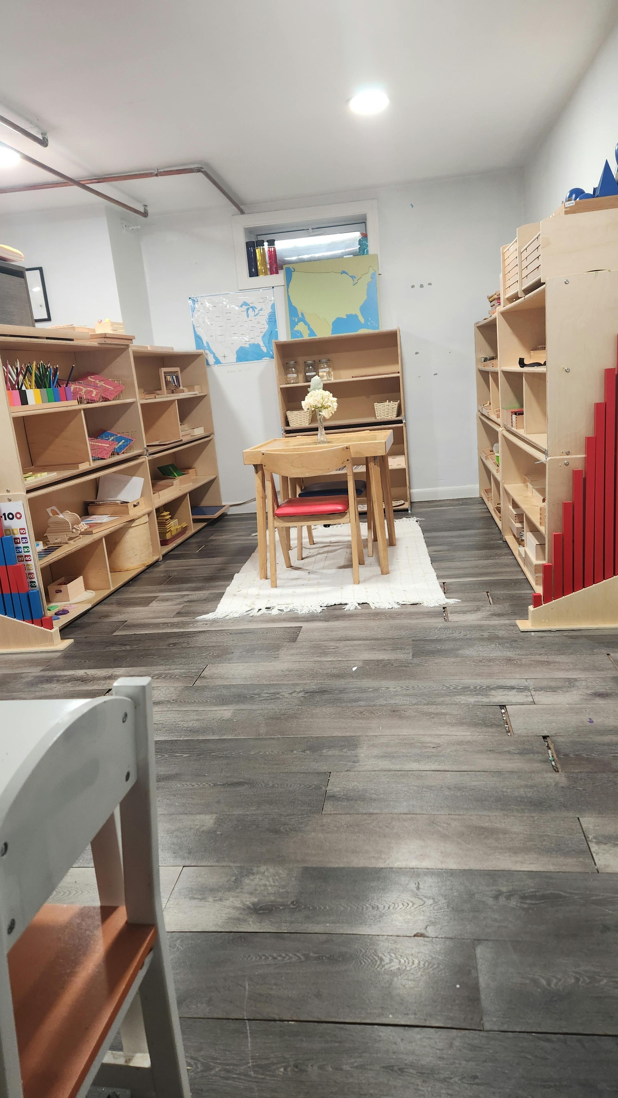Classroom with wooden shelves, a small table, and chairs