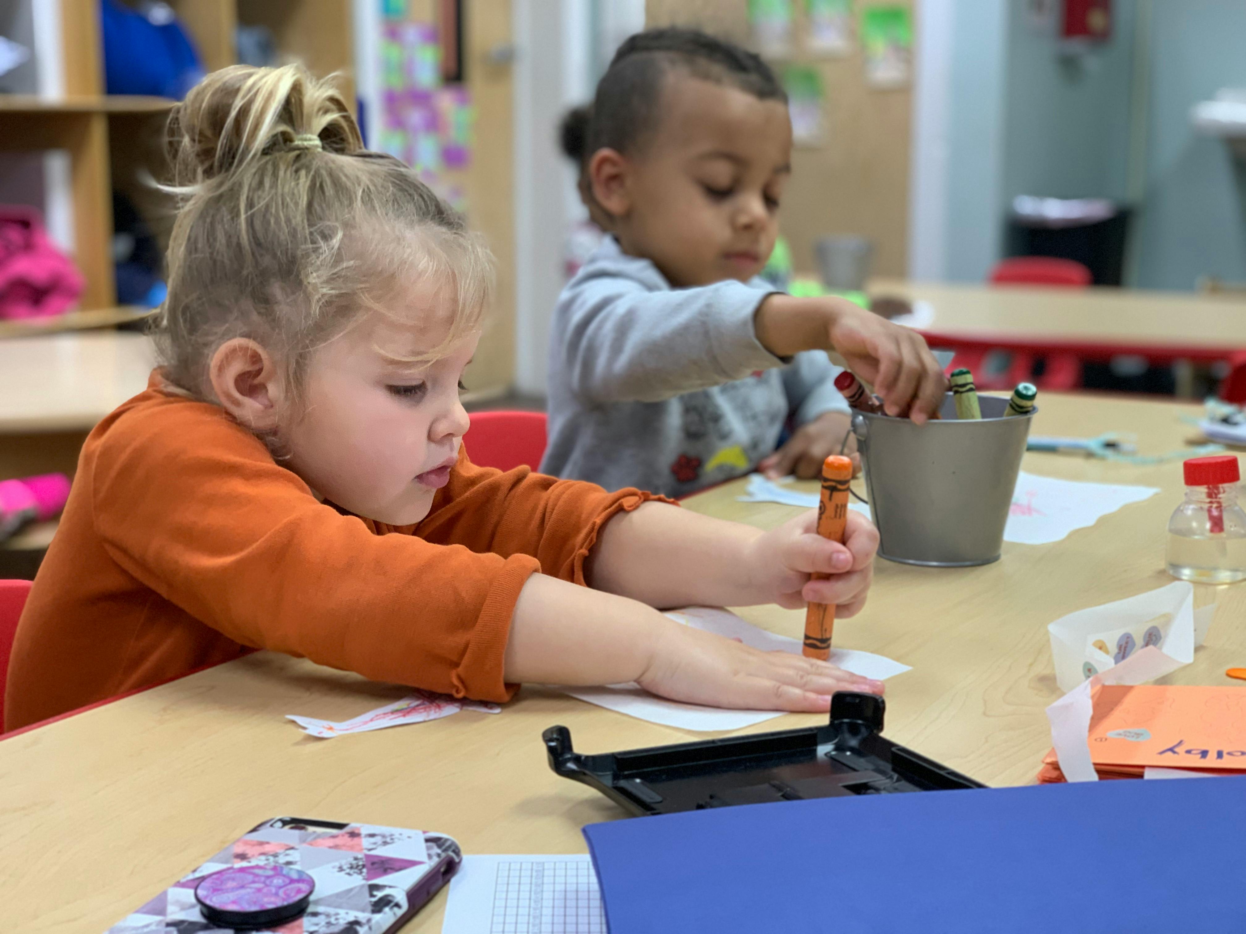 Two children drawing at a table in a classroom