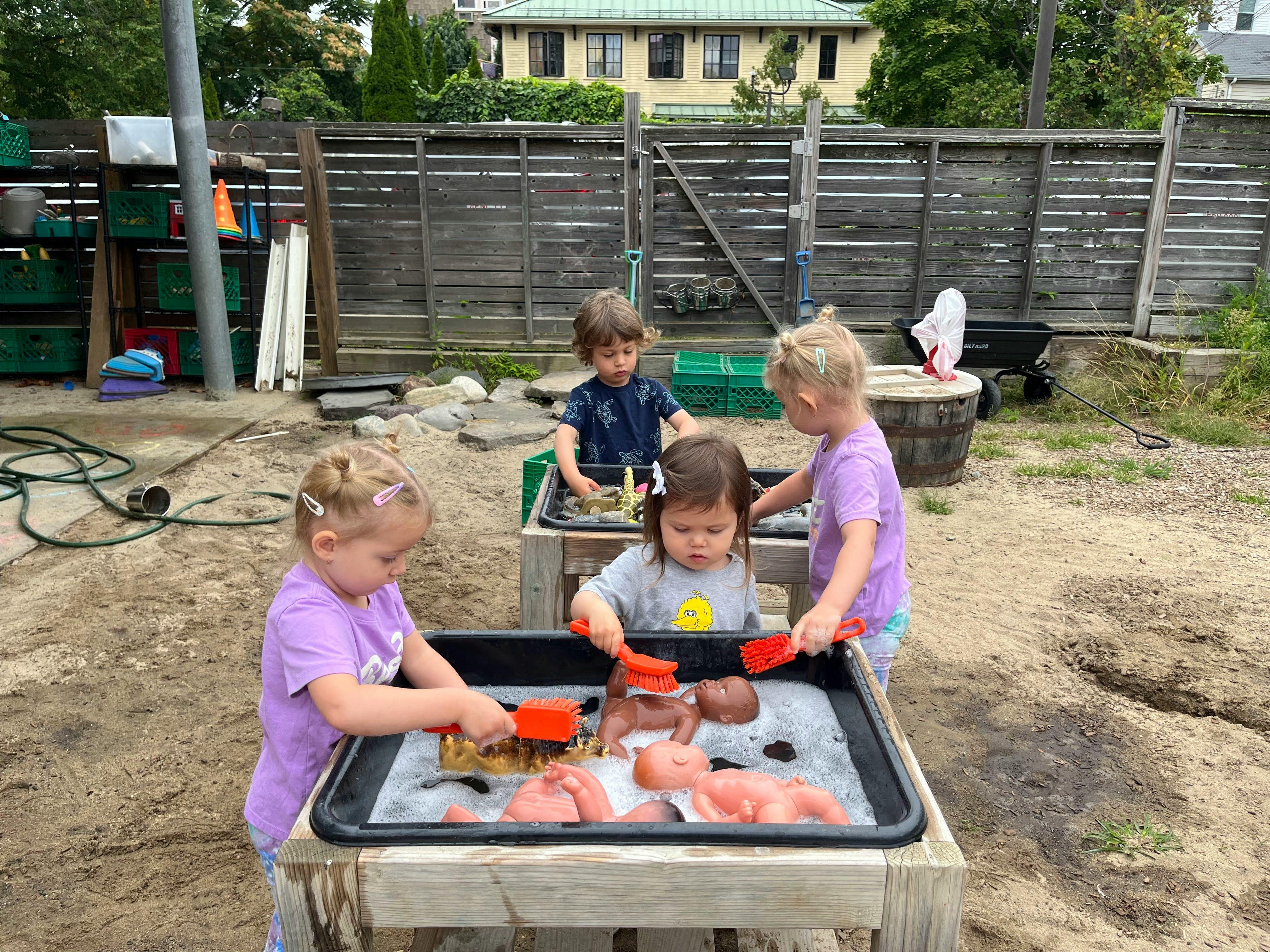 Children playing with dolls and water in outdoor sensory tables