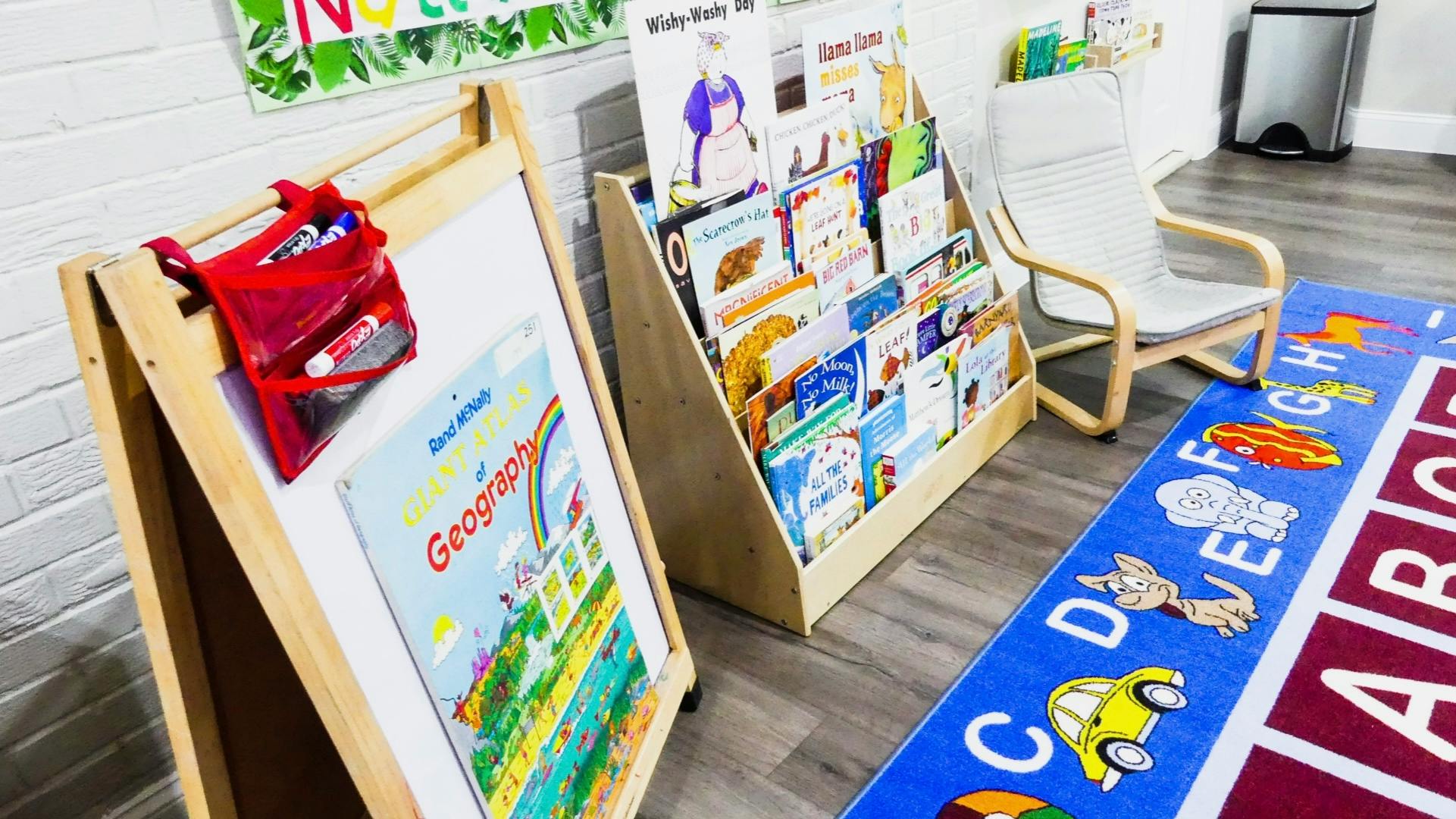 Easel with a book and a book display with a blue alphabet rug