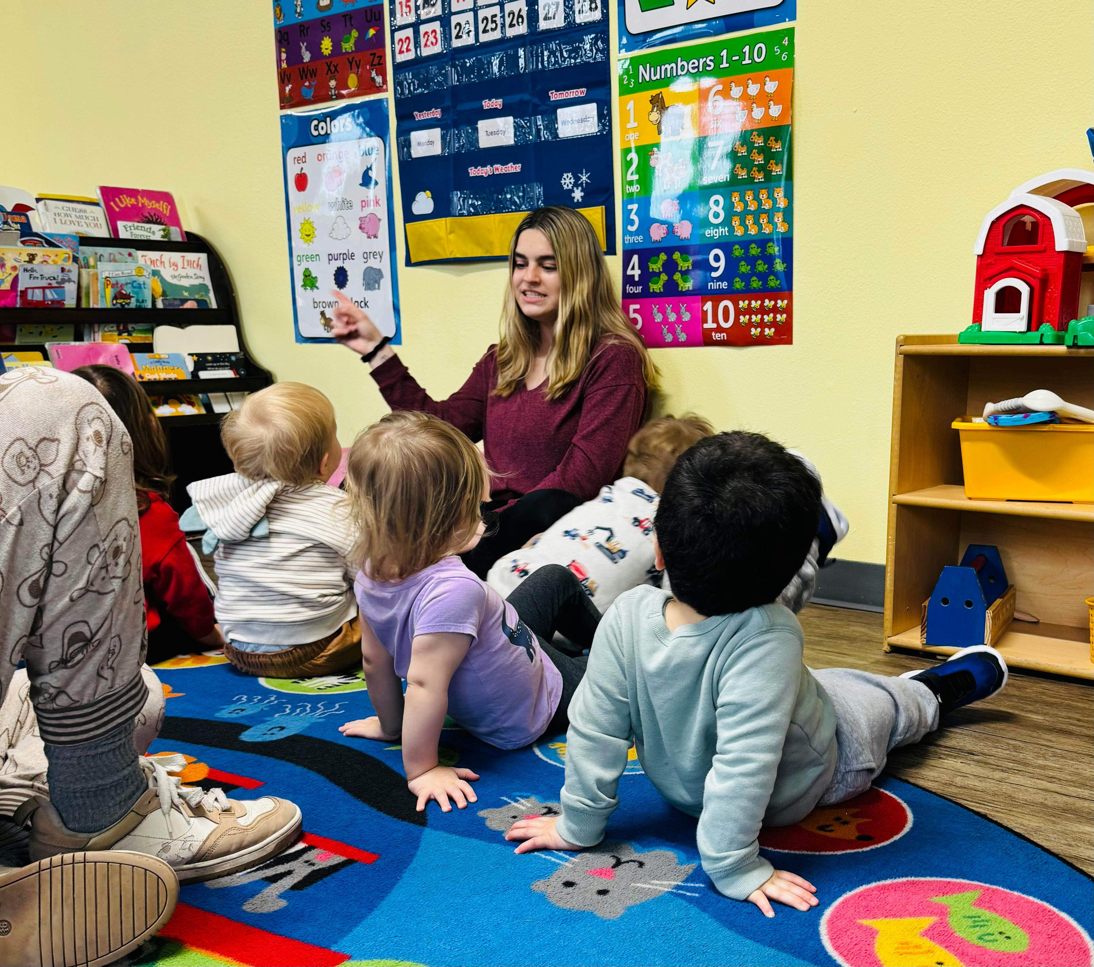 Teacher sitting on floor with young children in a classroom