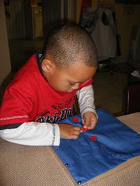 Child playing with red pieces on a blue mat
