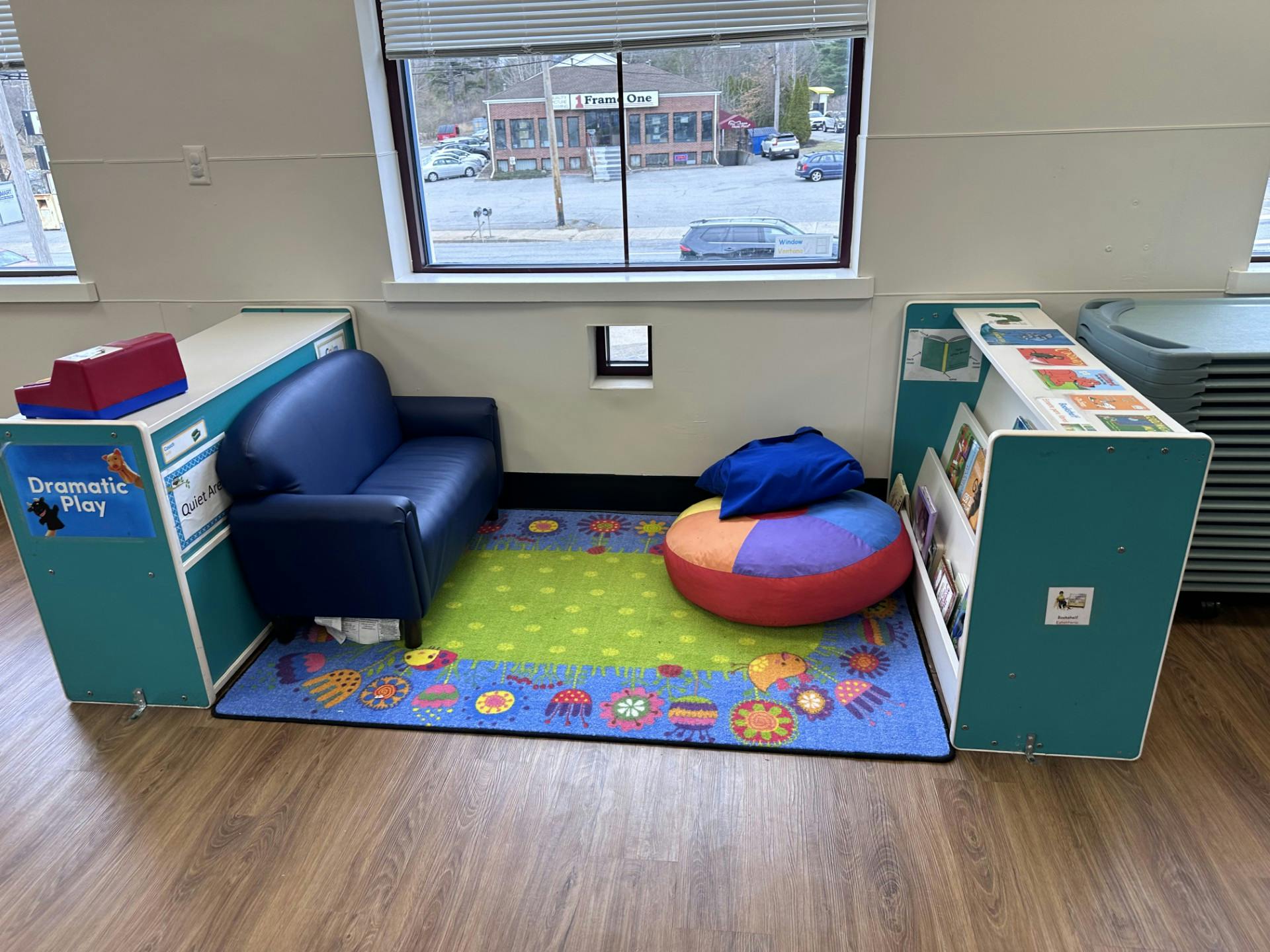 Small blue couch and colorful rug with a short bookcase in a classroom