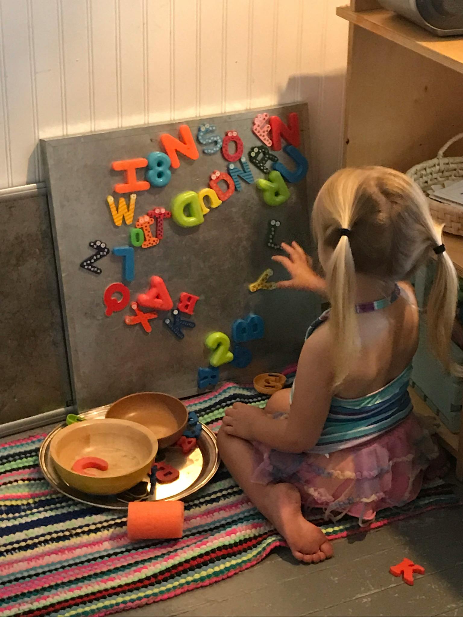 Child playing with magnetic letters and numbers on a board