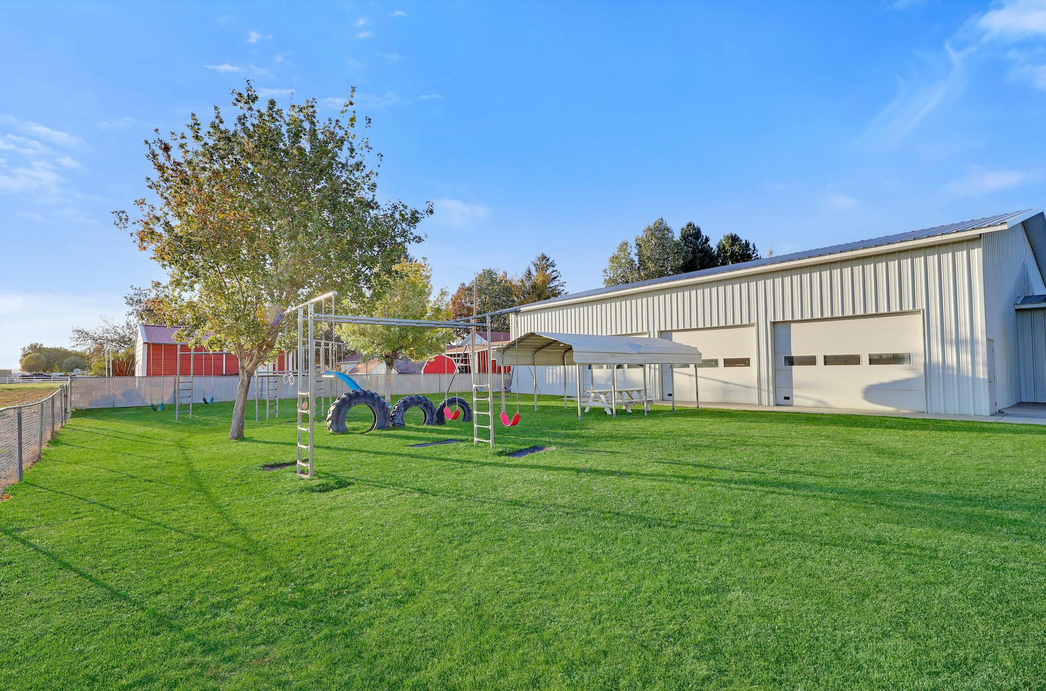 Playground with swings and climbing structure on a grassy lawn next to a large building