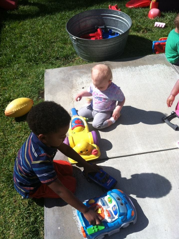 Child and baby playing with toys on concrete