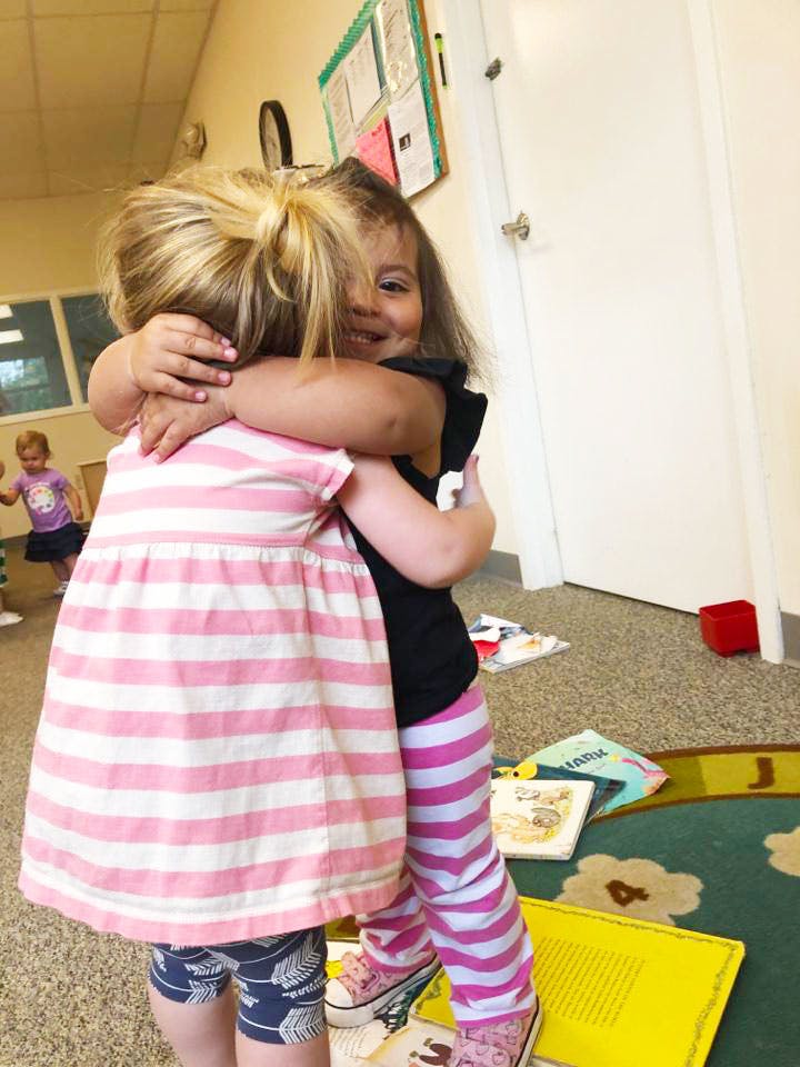 Two children hugging in a classroom