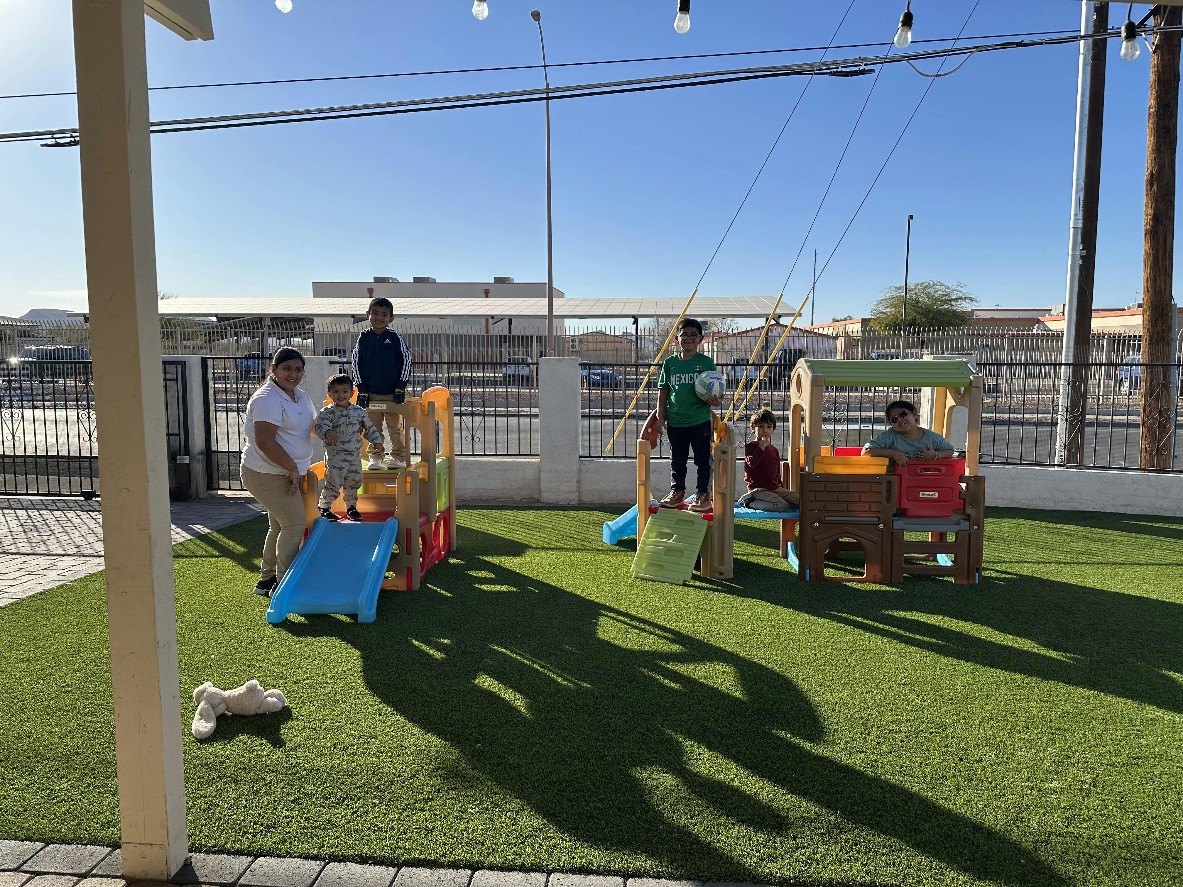 People and children on a playground with slides and play structures