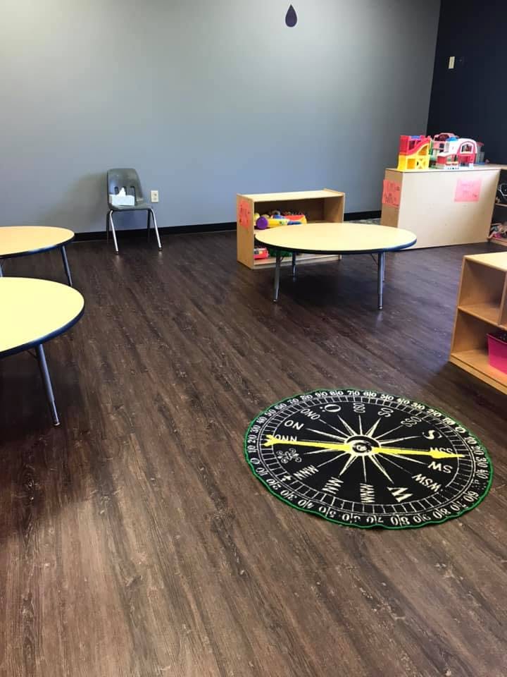 Classroom with small tables, chairs, and a compass rug