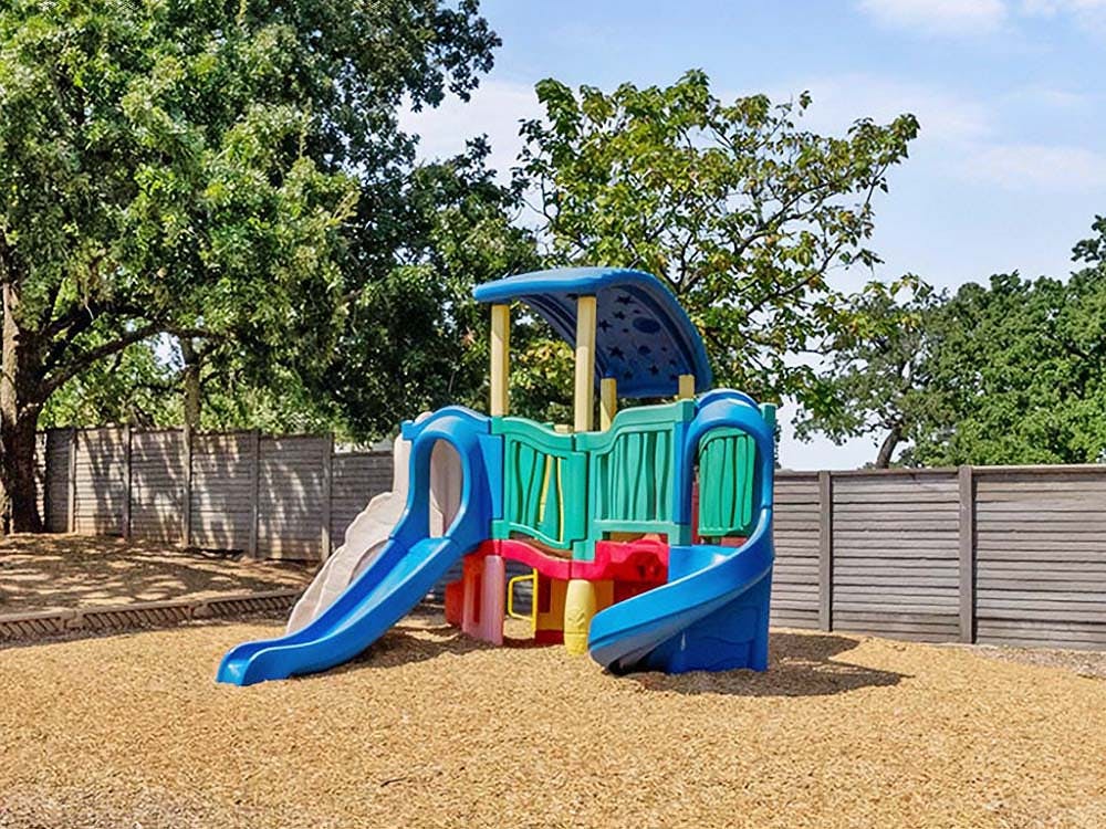 Colorful playground structure with slides on wood chip ground