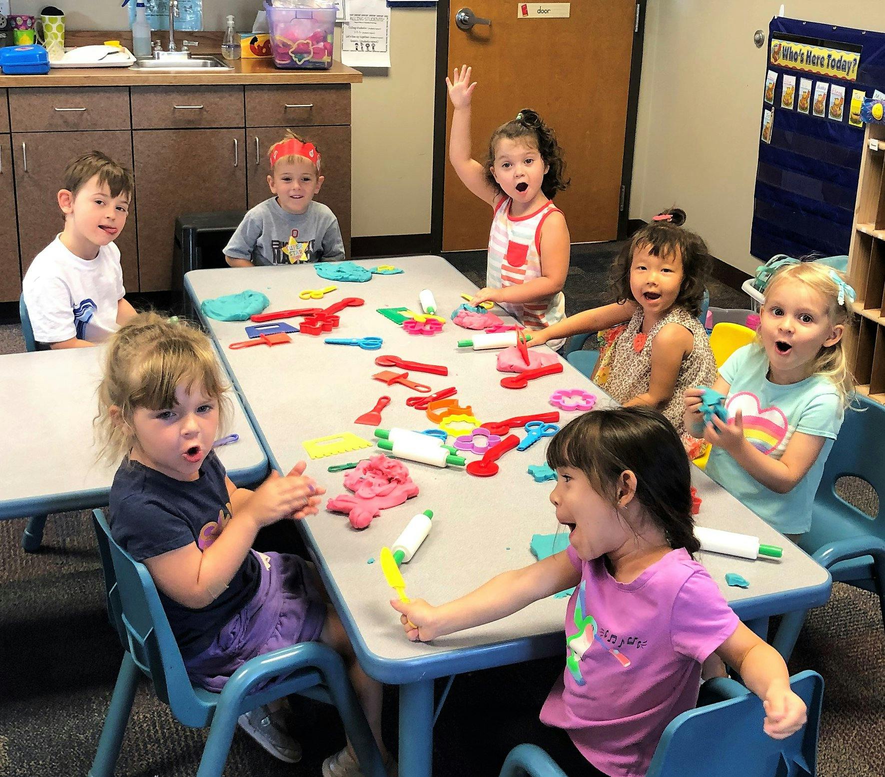 Children sitting at tables playing with colorful toys