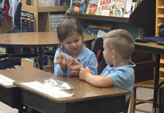 Two children at desks in a classroom