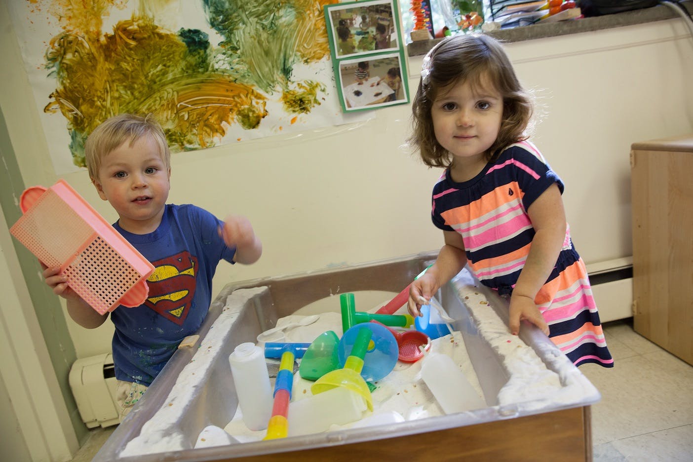 Two children playing with toys in a sand table