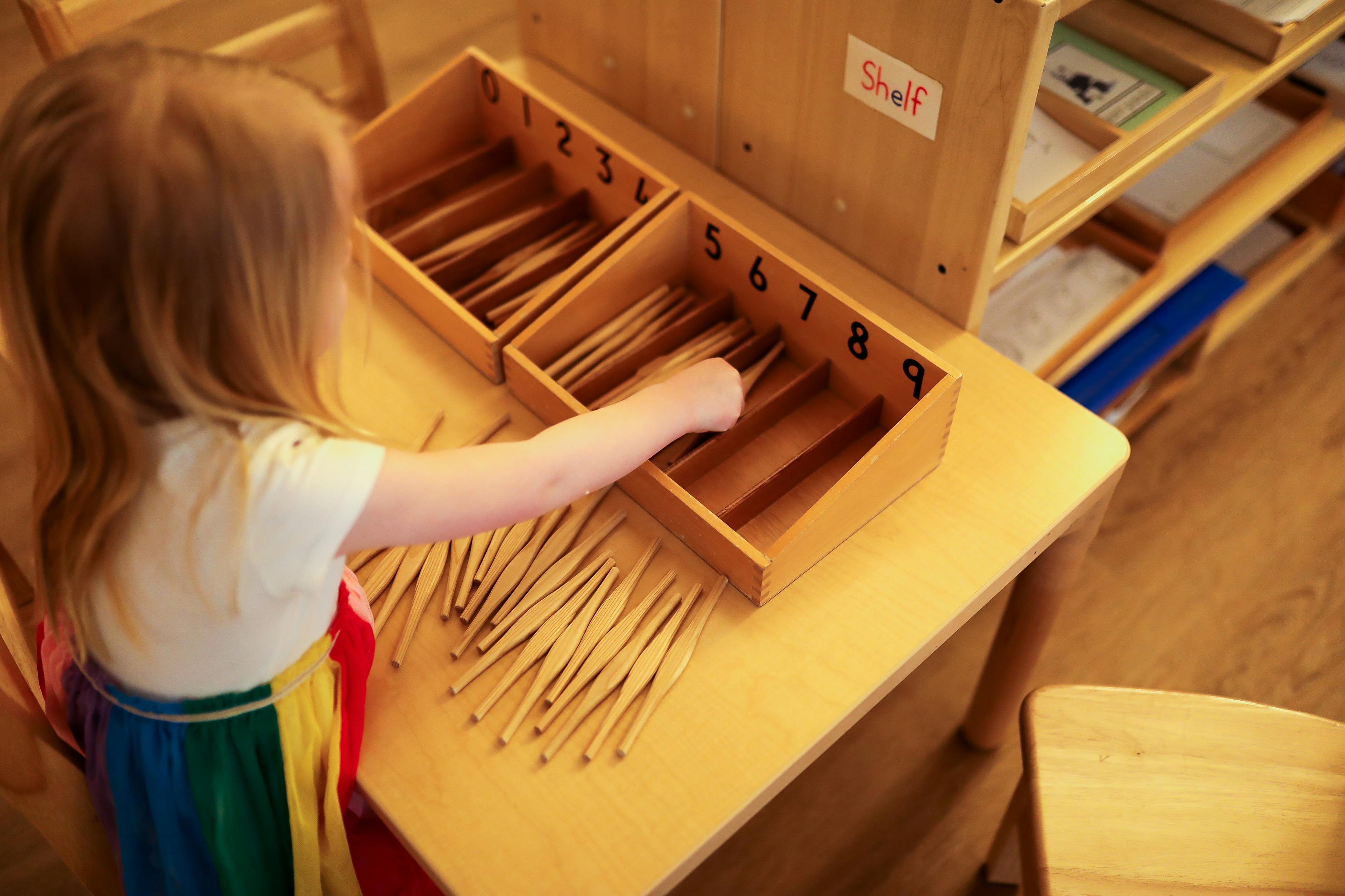 Child sorting wooden sticks into numbered boxes