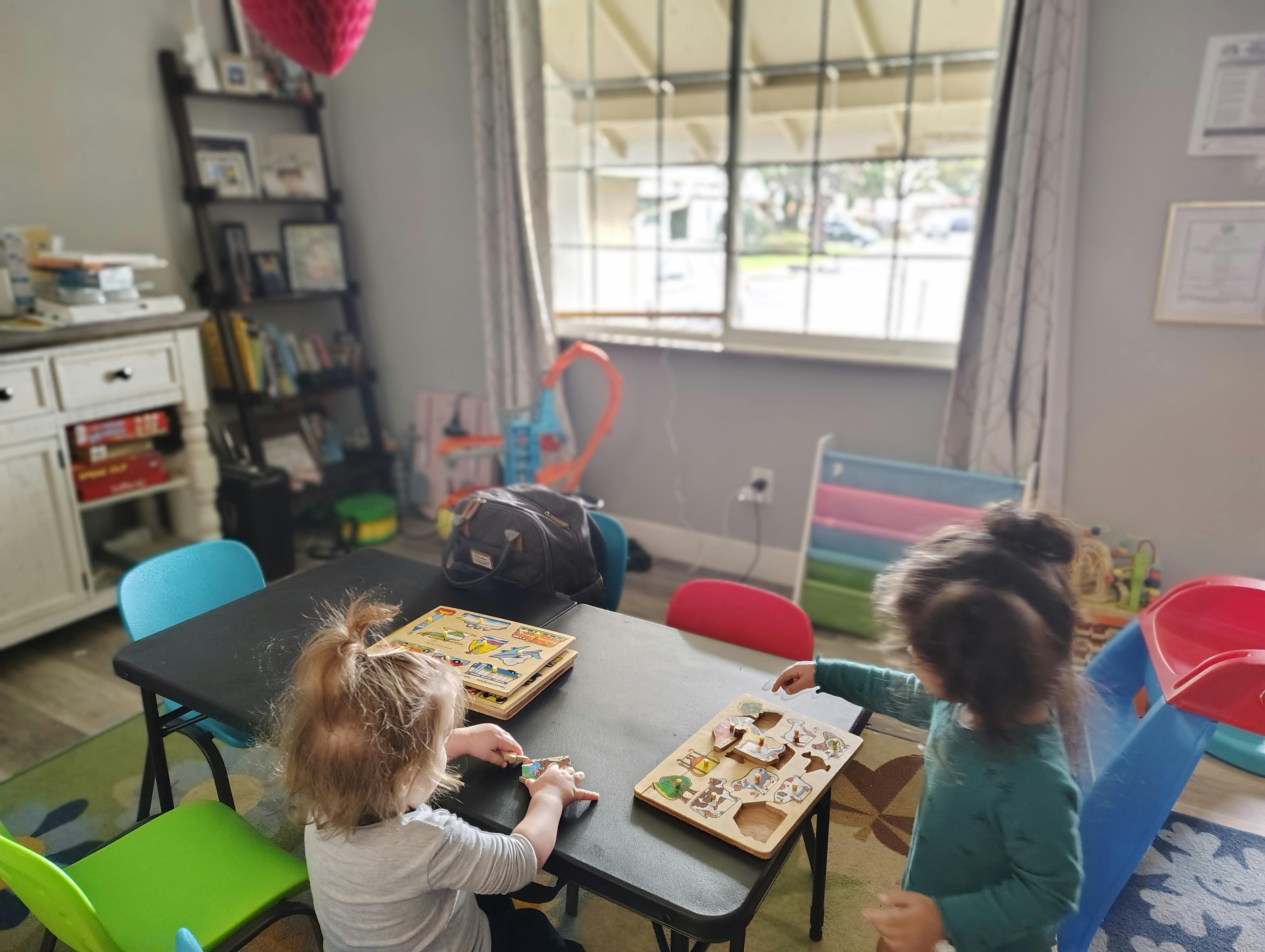 Two children playing with wooden puzzles at a table