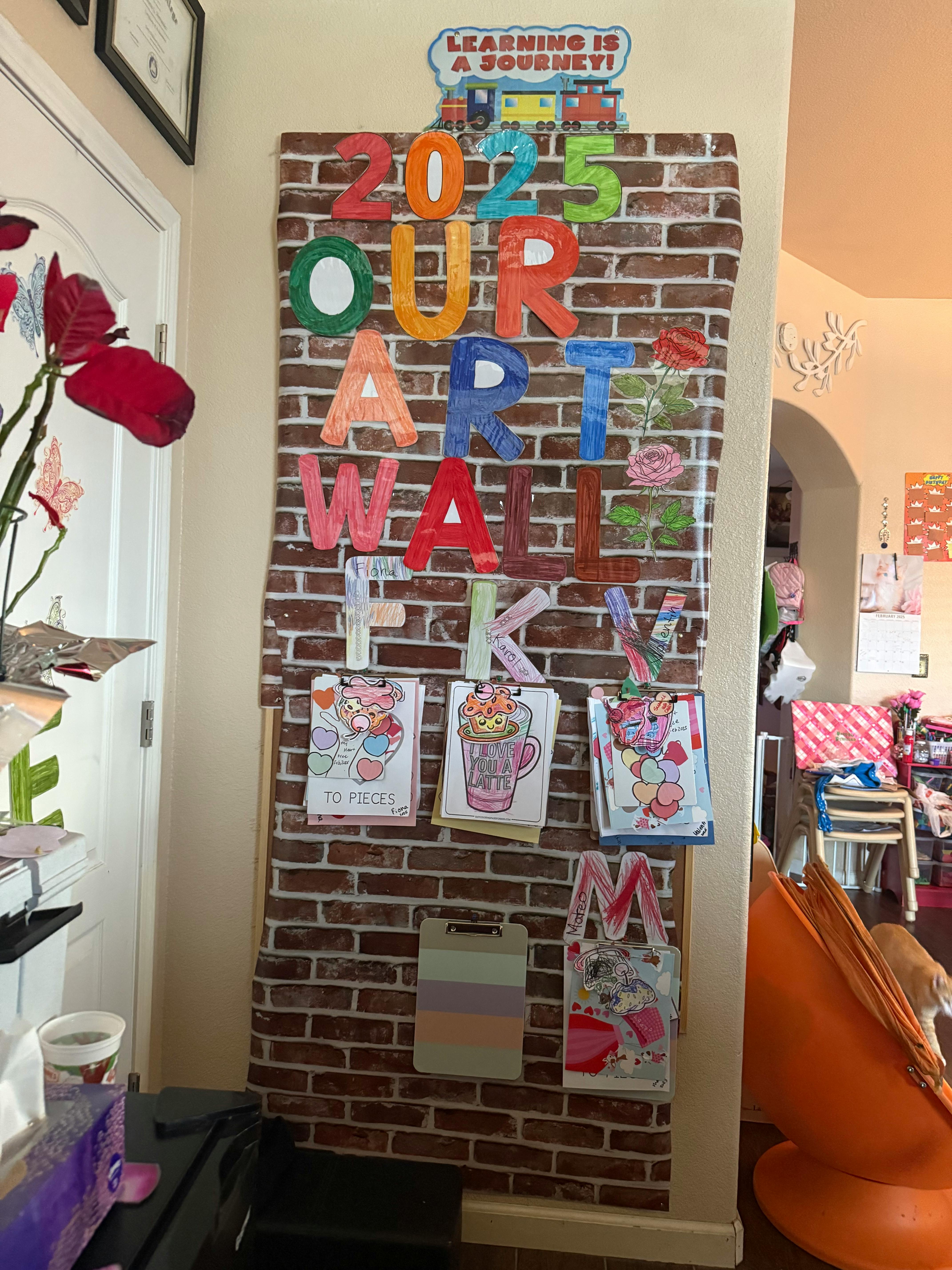 Art wall with colorful letters spelling "2025 Our Art Wall" and children's drawings