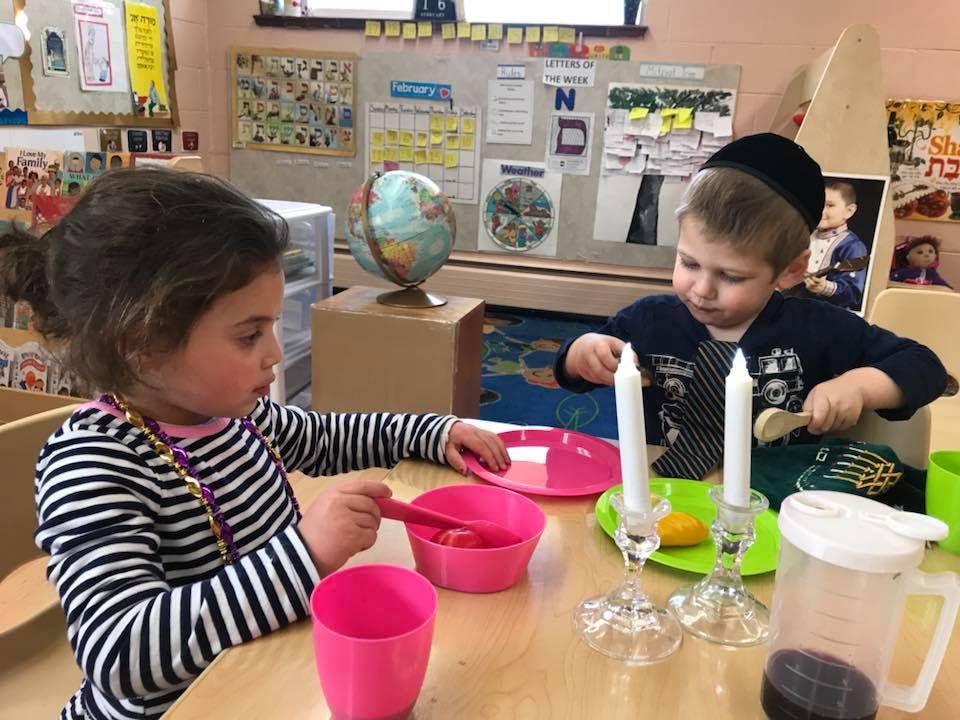 Two children at a table with plates, cups, and candles
