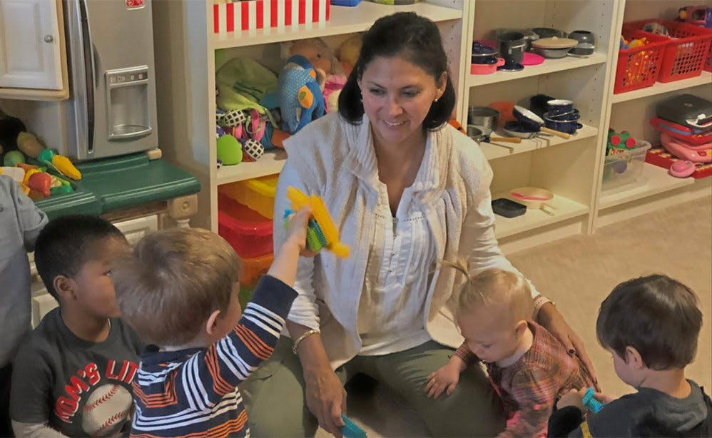 Adult person interacting with multiple children in a room