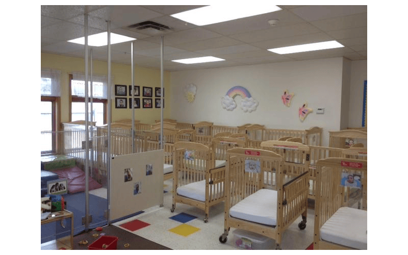 multiple wooden cribs with mattresses in a daycare room