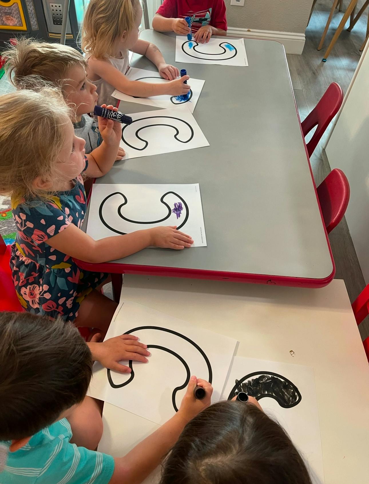 Children coloring shapes at a table