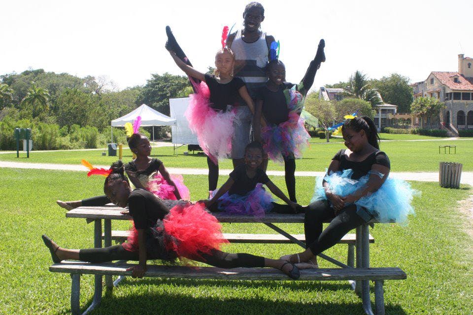 People in colorful tutus posing on and around a picnic table outdoors