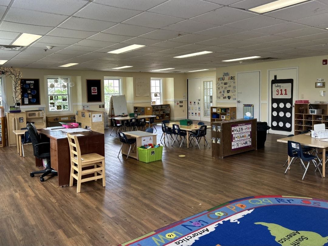 Empty classroom with small tables, chairs, and learning materials