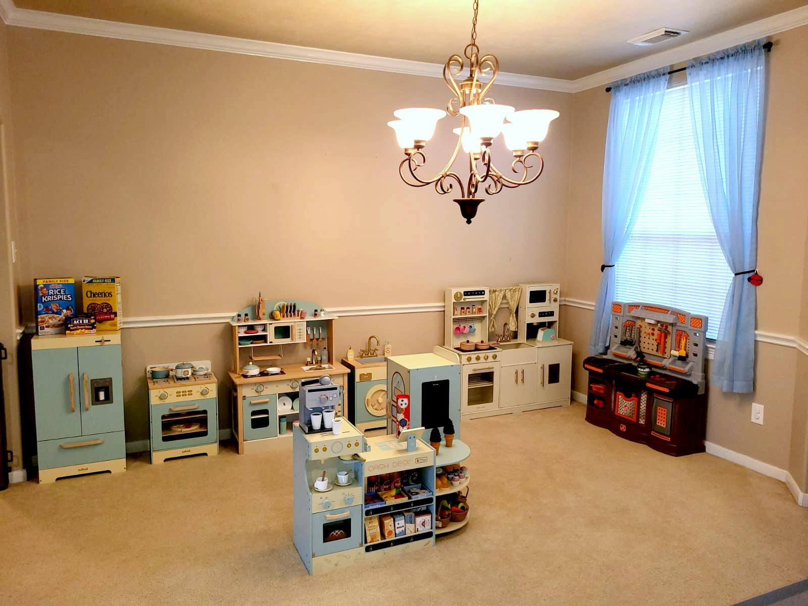 Room with multiple play kitchens and a chandelier