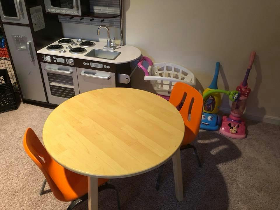 Play kitchen with a small round table and two orange chairs