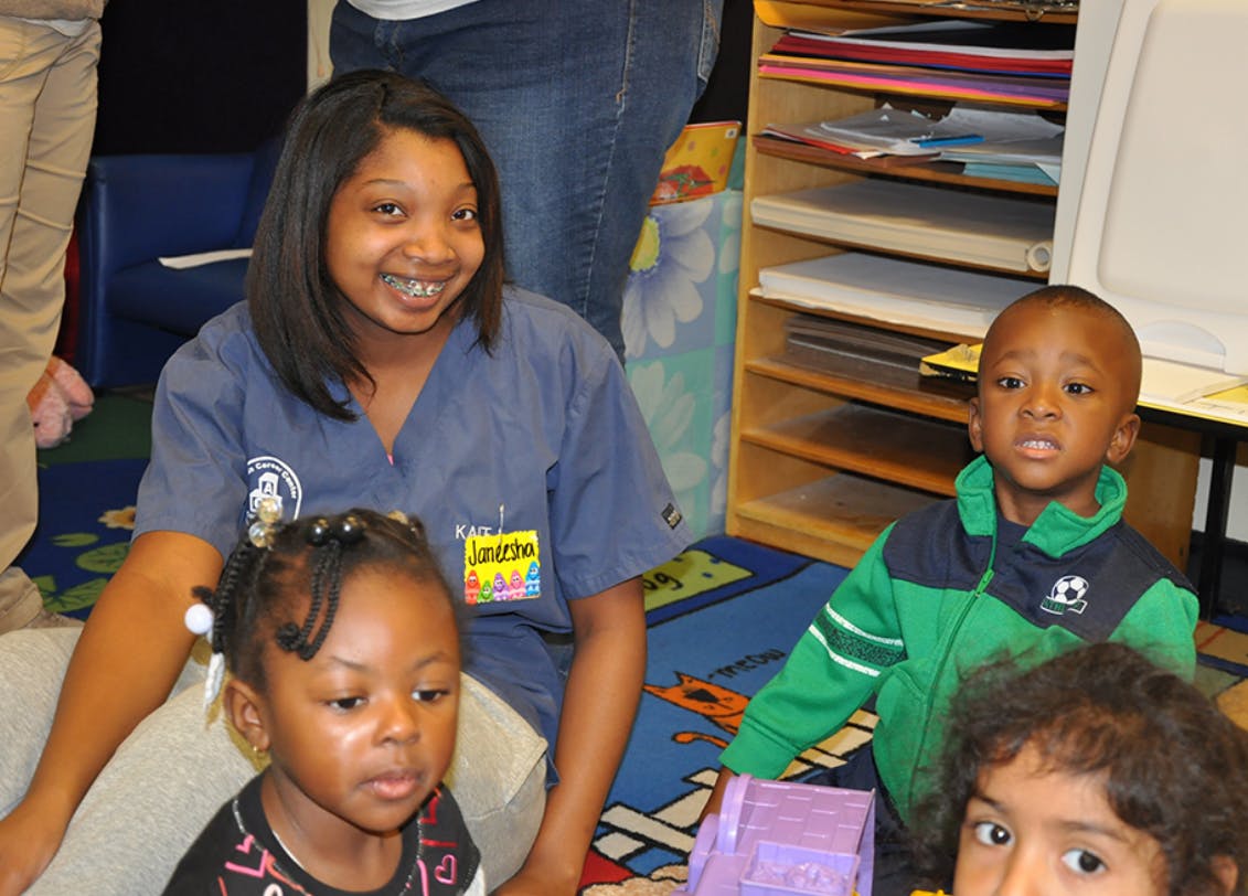 Person with two children and a teen in a classroom