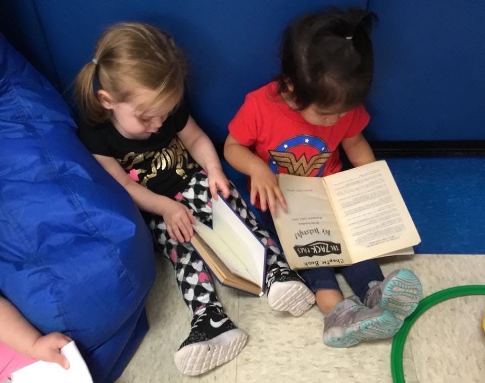 Two children sitting on the floor reading books
