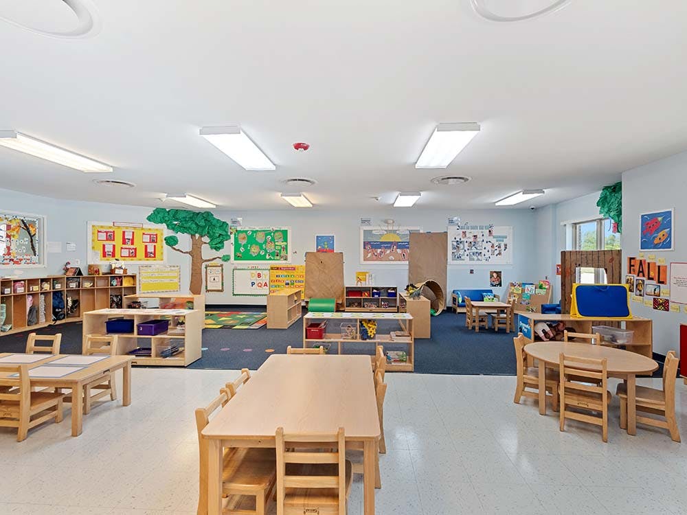 A colorful empty classroom with tables, chairs, and learning materials