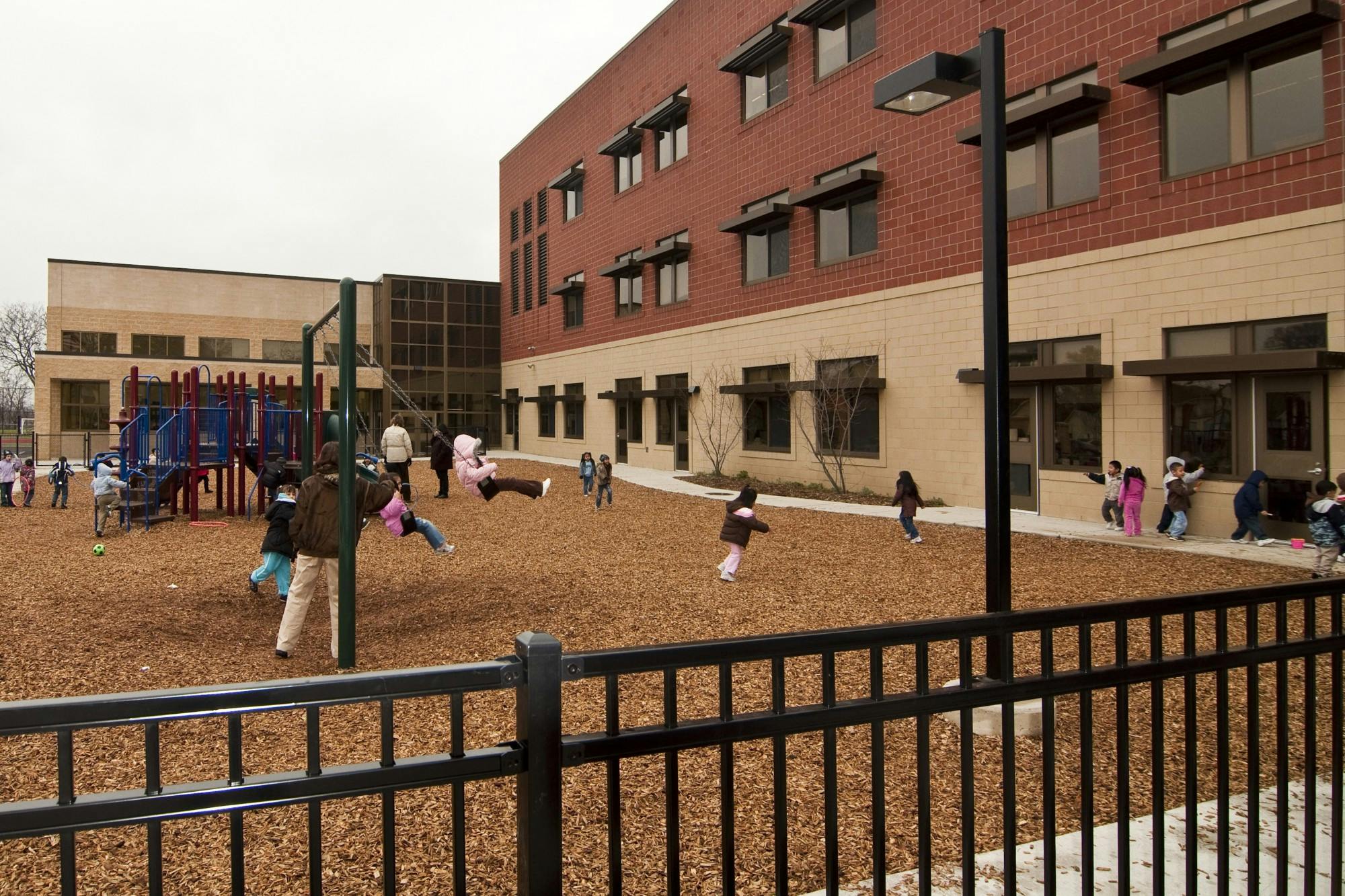 Children playing on a playground next to a school building