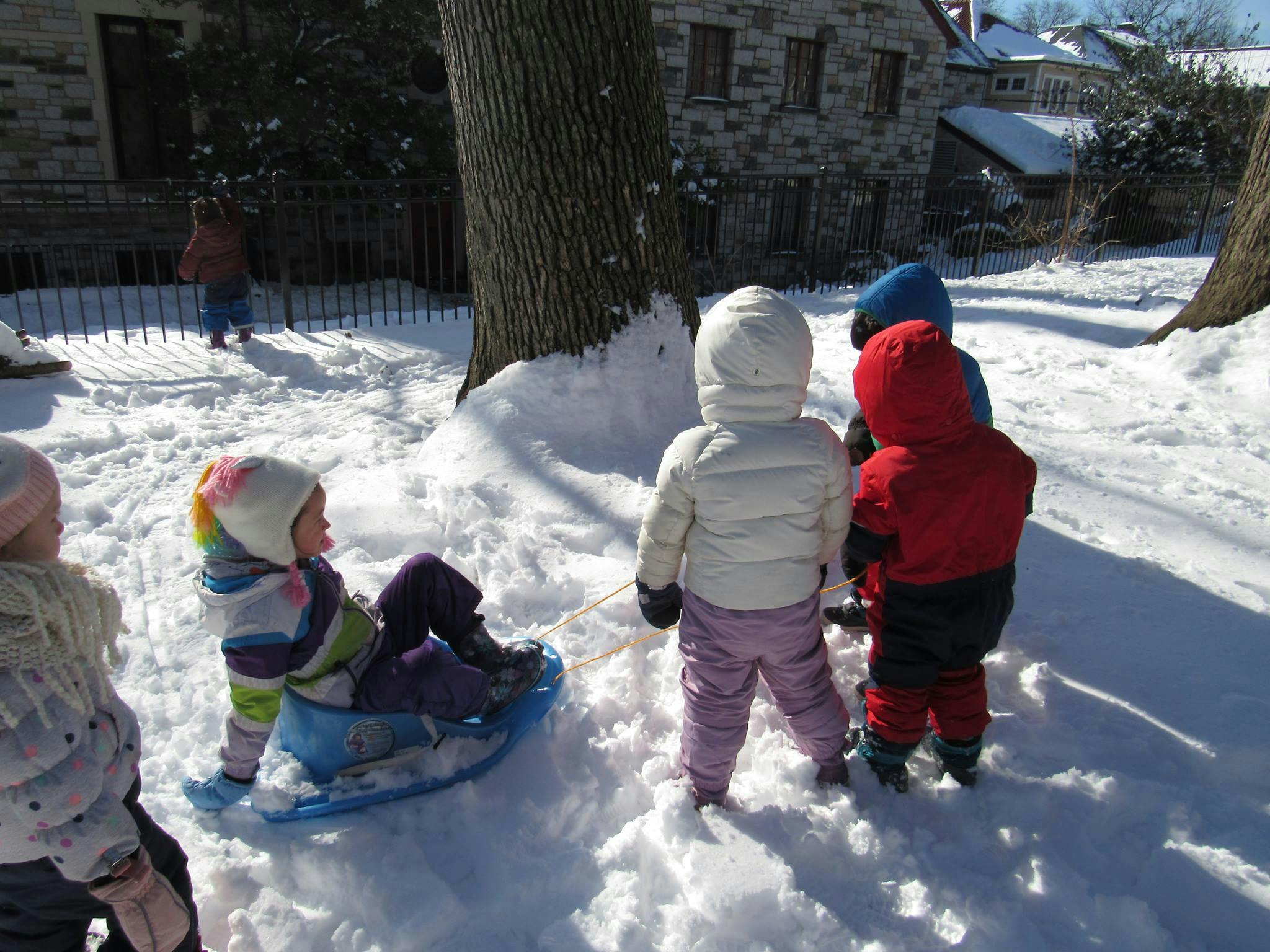 Children playing in snow with snow and a sled